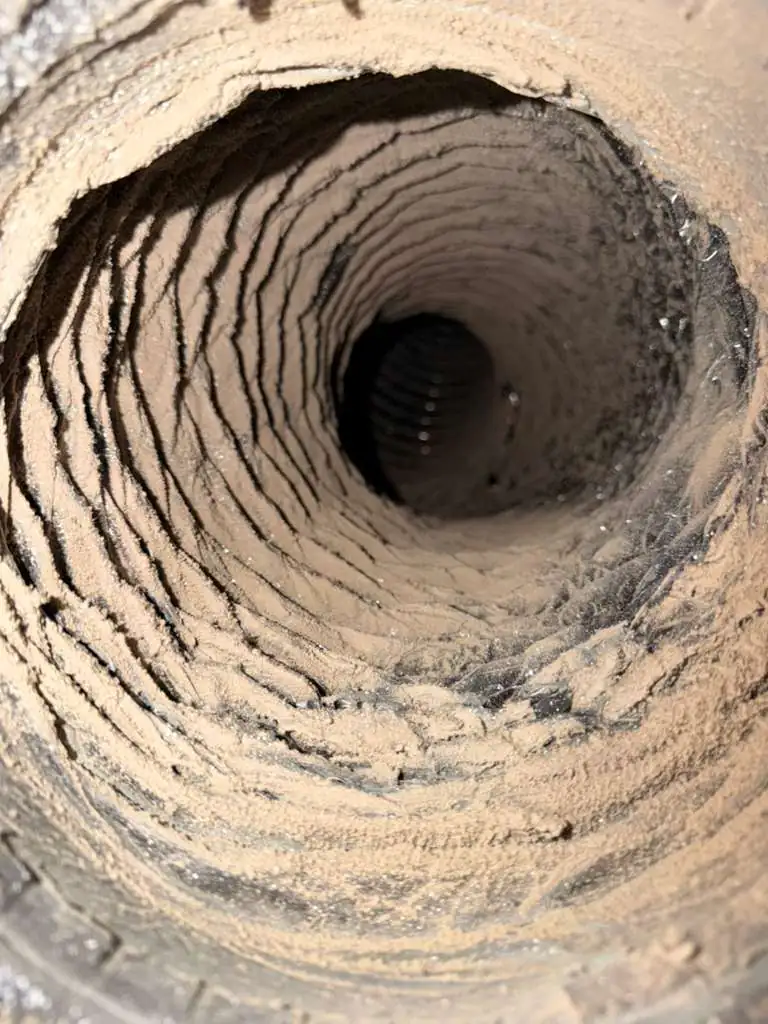 Close-up view of a dusty air duct interior, showcasing significant buildup of dust and debris, indicating a need for cleaning to improve indoor air quality and HVAC efficiency.